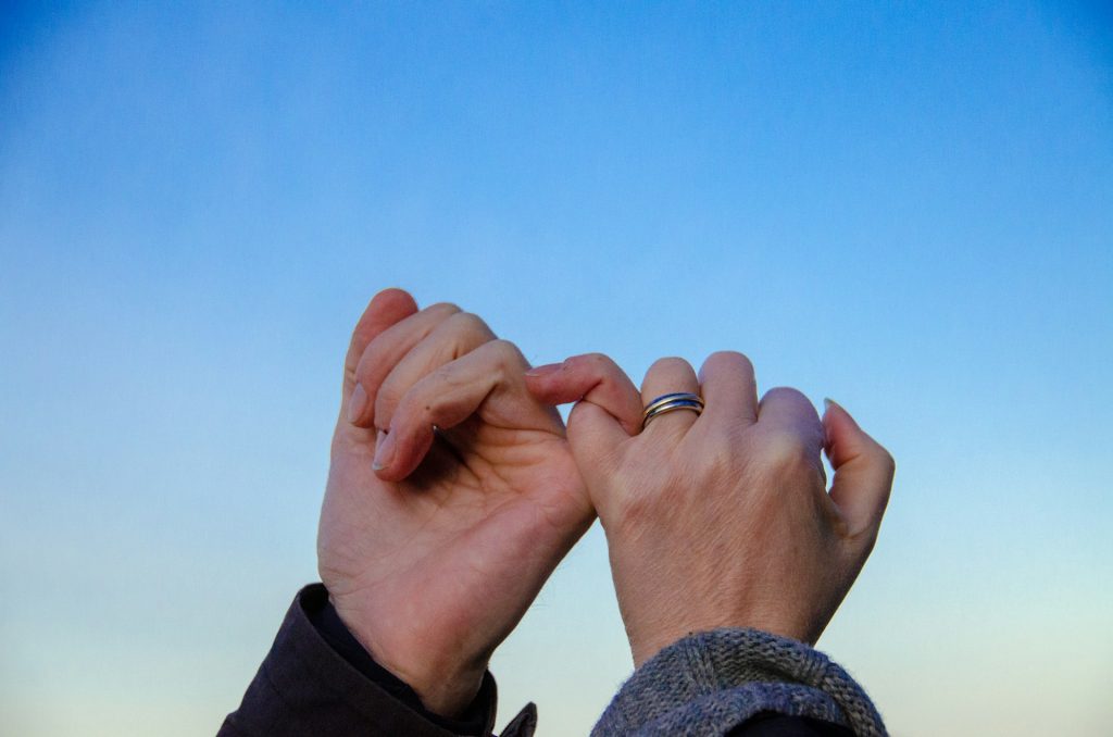 two hands pinky promising as a huorous reference to the legally binding nature of a memorandum of agreement in malaysia